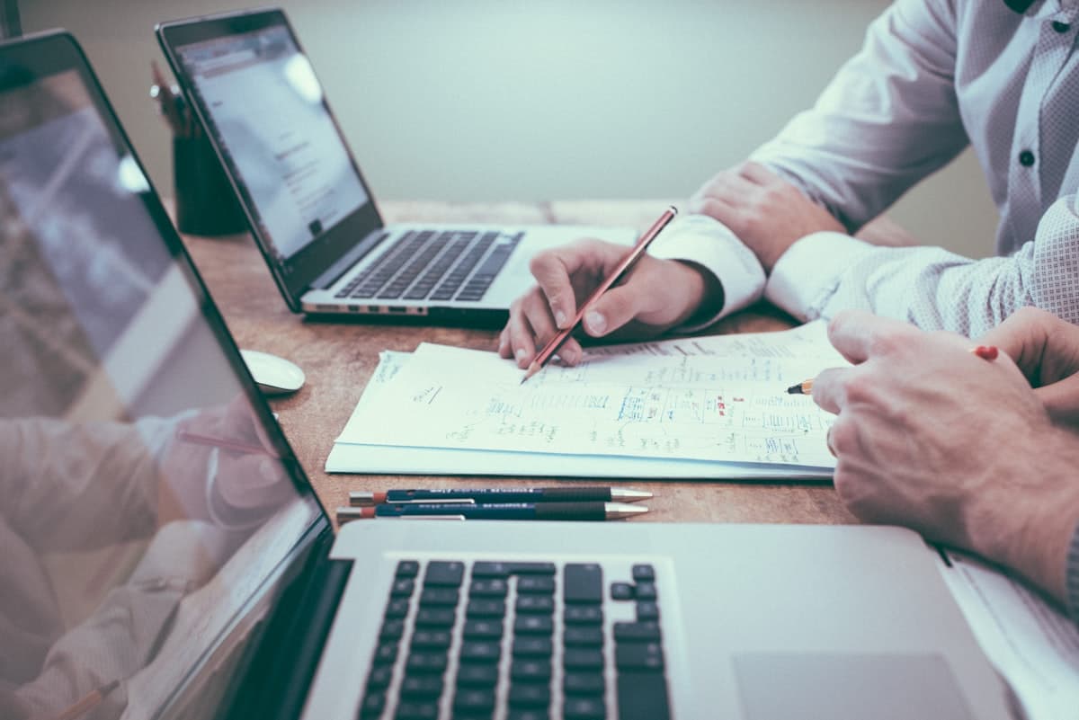 Responsable d'organisme de formation prenant des notes à son bureau près d'une fenêtre, ambiance feutrée